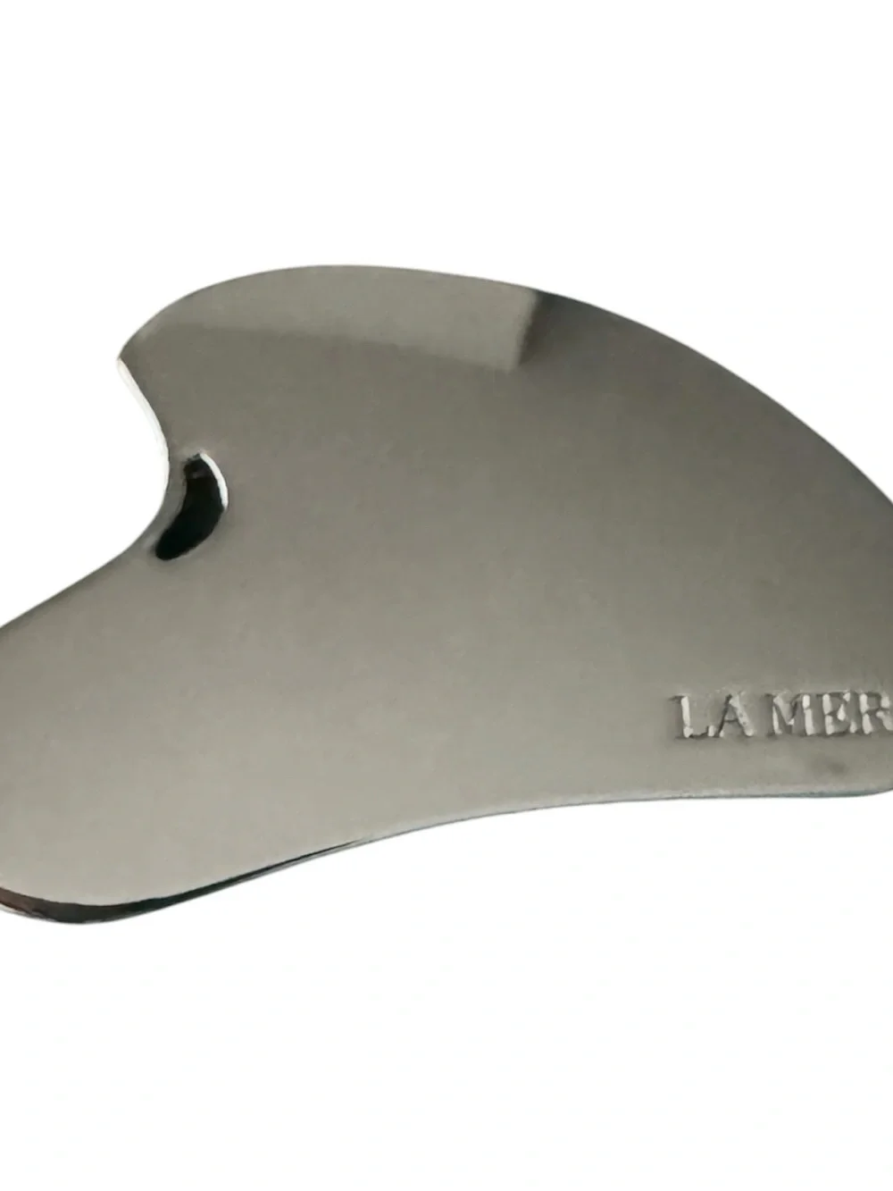 La Mer Silver Stainless Steel Gua Sha on Green Velvet Pouch and cosmetic bag